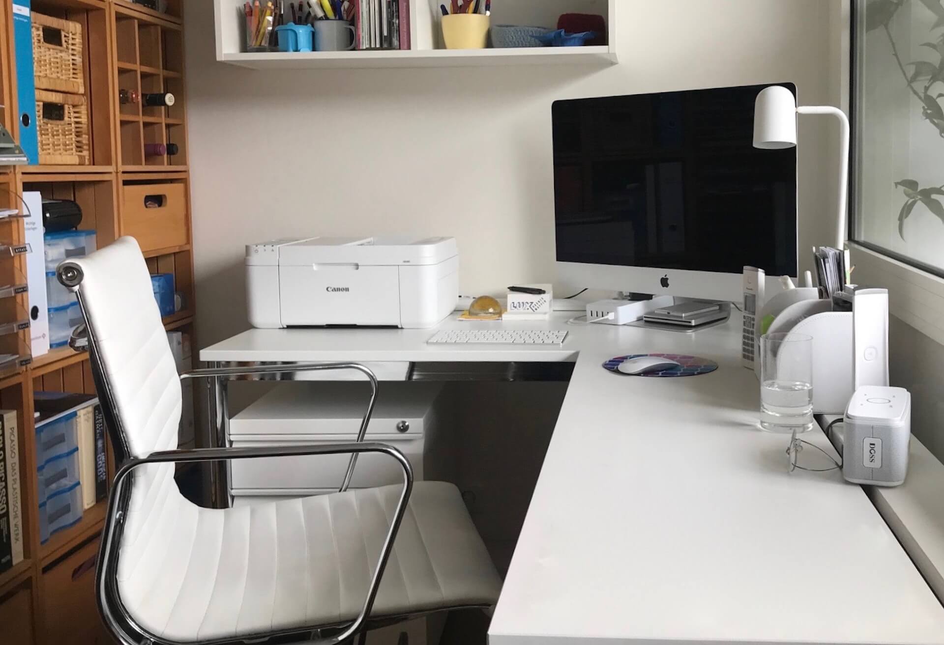  A home office with a white desk, computer, printer, and other office supplies.